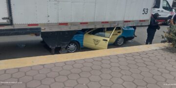 Taxista vive para contarla al quedar con su taxi incrustado debajo de un remolque en Quecholac